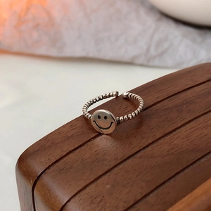 Close-up of vintage smile face ring with twisted rope texture on wooden base