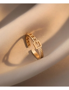 Détail macro d'une bague boucle de ceinture dorée avec motif G et zircons brillants