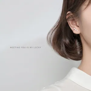 Minimalistische S925 Silber Ohrstecker mit drei Zirkonia Blumen auf asiatischem Modell