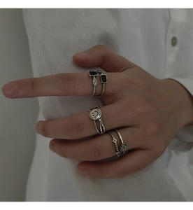 Close-up of vintage S925 silver smiley face and black onyx cross rings on a hand
