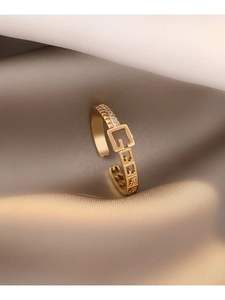 Détail macro d'une bague dorée ajustable avec zircons pavés et motifs ajourés en G