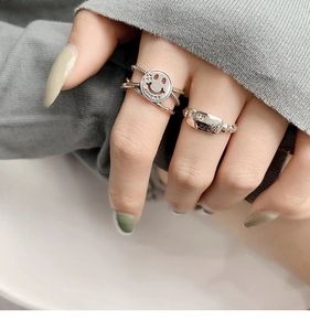 Close-up of retro S925 silver smiley face ring and rectangle tag ring with 2005 engraving