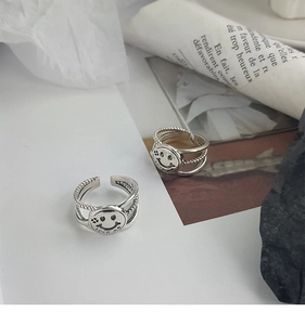 Detailed close-up of double-layer vintage s925 silver smiley face ring on newspaper background
