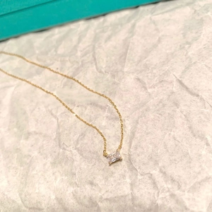 Dettaglio della collana dorata con ciondolo geometrico in cristallo taglio smeraldo