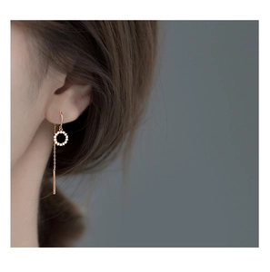 Détail de boucles d'oreilles traversantes en or rose avec cercle serti de zircons