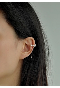 Close-up of gold pearl ear cuff with long tassel chain on model's ear in minimalist style