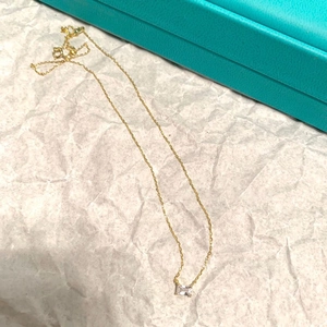 Dettaglio della collana dorata con pendente in zircone quadrato su sfondo di carta bianca