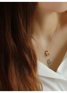 Dettaglio di collane a strati in oro e argento con pendente ovale su una modella