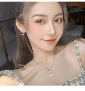 Gros plan d'un collier avec pendentif éventail et boucles d'oreilles rose doré