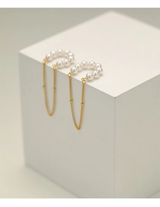 Detailed close-up of vintage pearl tassel clip-on earrings on a white display stand