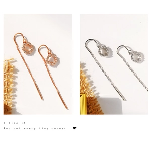 Détail de boucles d'oreilles à pompons cerclés d'argent avec cristaux en or rose et argent