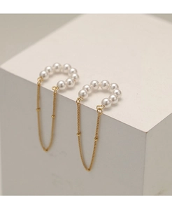 Detail of vintage gold pearl tassel ear cuffs with delicate long fringe on white stone