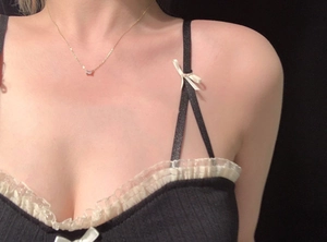 Primo piano di una collana dorata con pendente quadrato trasparente su top con pizzo