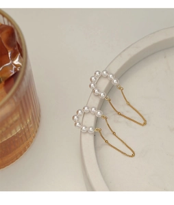 Detail of vintage pearl tassel earrings with gold chain on white stone tray