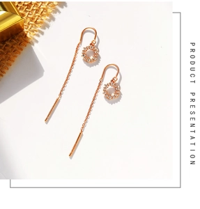 Détail de boucles d'oreilles cercle à pompons or rose avec zircons blancs et chaînes en métal
