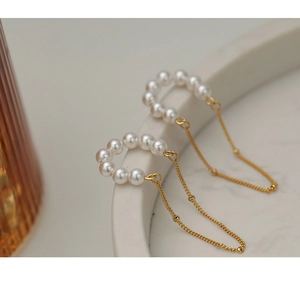 Detail of vintage pearl tassel clip earrings hanging on a ceramic tray rim