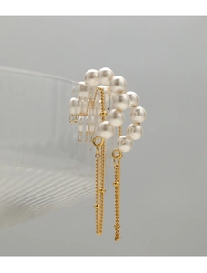 Detailed macro view of vintage pearl tassel earrings with golden chains on glass
