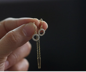 Détail de boucles d'oreilles pampilles dorées avec cercle pavé de zircons et chaînes