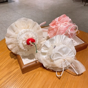 Gros plan de serre-têtes Lolita en dentelle rose et crème ornés de perles et cerises