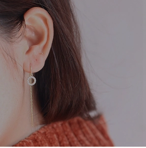 Vue macro de boucles d'oreilles pendantes dorées avec cercles strass sur un mannequin