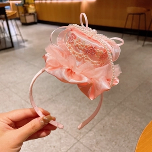 Détail du serre-tête mini chapeau rose avec nœud en soie, dentelle et perles nacrées