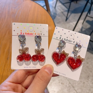 Detail of red cherry and heart resin clip-on earrings for kids with glitter and rhinestones
