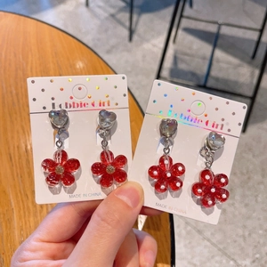 Detailed view of red resin flower clip-on earrings for kids with heart gemstone accents