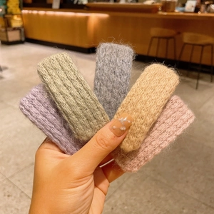 Détail de cinq barrettes en laine tricotée en tons violet vert gris crème et rose