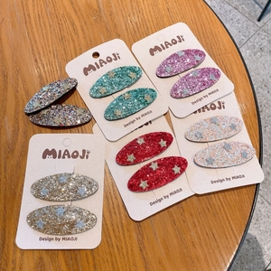 Detail of glitter star hair clips in multiple colors on branded display cards