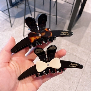 Détail de pinces à cheveux oreilles de lapin avec nœud et strass en acétate