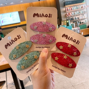 Close-up of three glitter hair clips sets in pink green red with gold stars