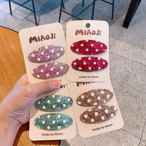 Dettaglio di fermagli per capelli glitterati a pois in quattro colori su carta MIAOJI
