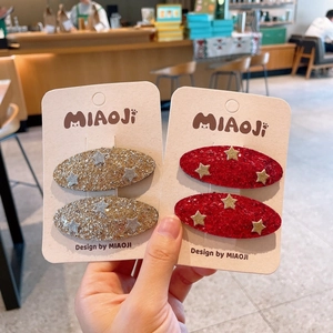 Close-up of glitter hair clips with star patterns in gold and red for young girls