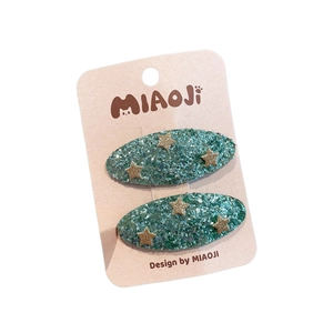Sparkly green glitter hair clips with gold star sequins on display card for little girls