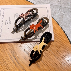 Set di tre mollette per capelli a forma di gatto leopardato su tavolo in legno