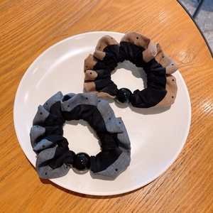 Polka dot pleated scrunchies with large beads on a white plate and wood background