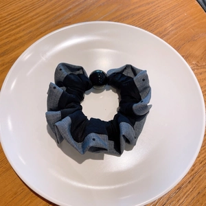 Close-up of polka dot and satin hair scrunchie with a large black bead on a white plate