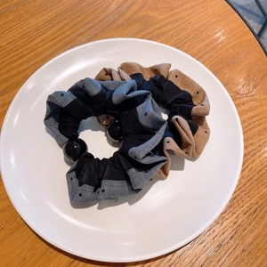 Elegant polka dot scrunchie set with black decorative beads on a minimalist plate