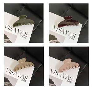 Detail of four acetate hair claws in Morandi colors with gold lettering and glossy finish