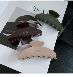 Close-up of three Morandi color acetate hair claws on a magazine with glossy finish