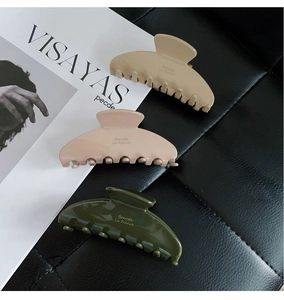 Detailed shot of three acetate hair claws in matte apricot, pink and glossy dark green