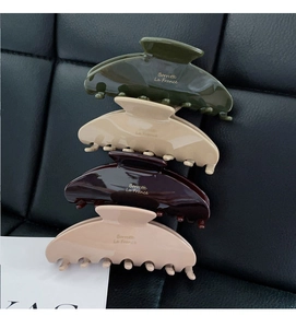 Vertical stack of acetate claw clips in Morandi colors on black leather background
