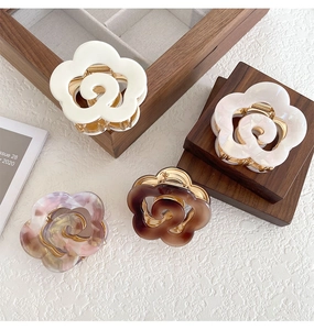 Detailed view of 4-pack acetate floral hair claws with elegant gold metal spring teeth