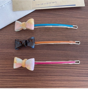 Close-up of marble-textured acetate bow hair clips in blue, orange, and pink colors