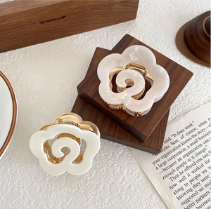 Detailed view of white and pearlescent flower hair claws with sturdy gold metal clips