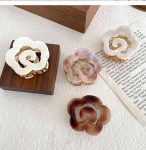 Detailed macro view of four acetate floral hair claws in marble and pearlescent finishes