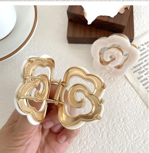 Detail of white rose hair claw clip showing gold alloy spring and pearlescent texture