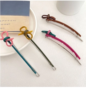 Macro view of vintage-style resin bow hair clips with silver metallic bases in multiple colors