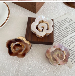 Three elegant flower hair claws in pearl white, tortoiseshell and purple marble finishes