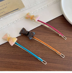 Detailed view of three colorful acetate bow hair clips with marble texture and metal base